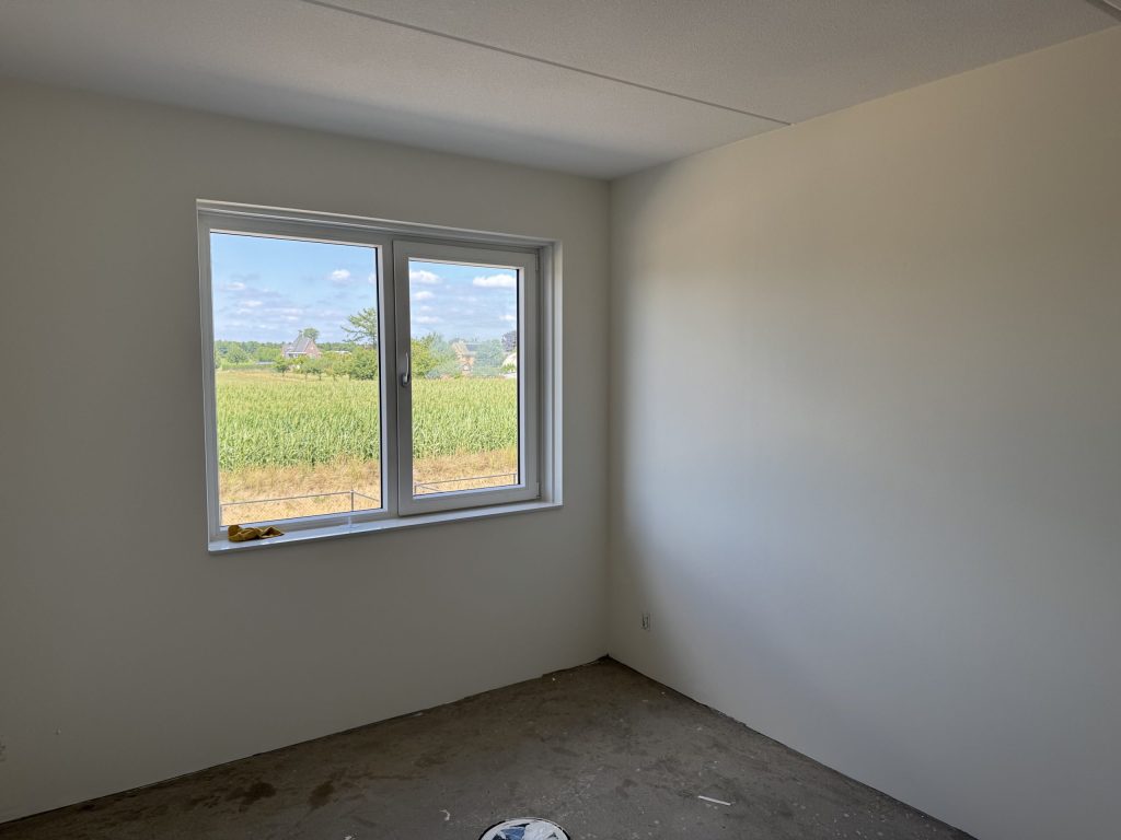 Lege slaapkamer met gladde lichte wanden en een raam, nog voor de verhuizing